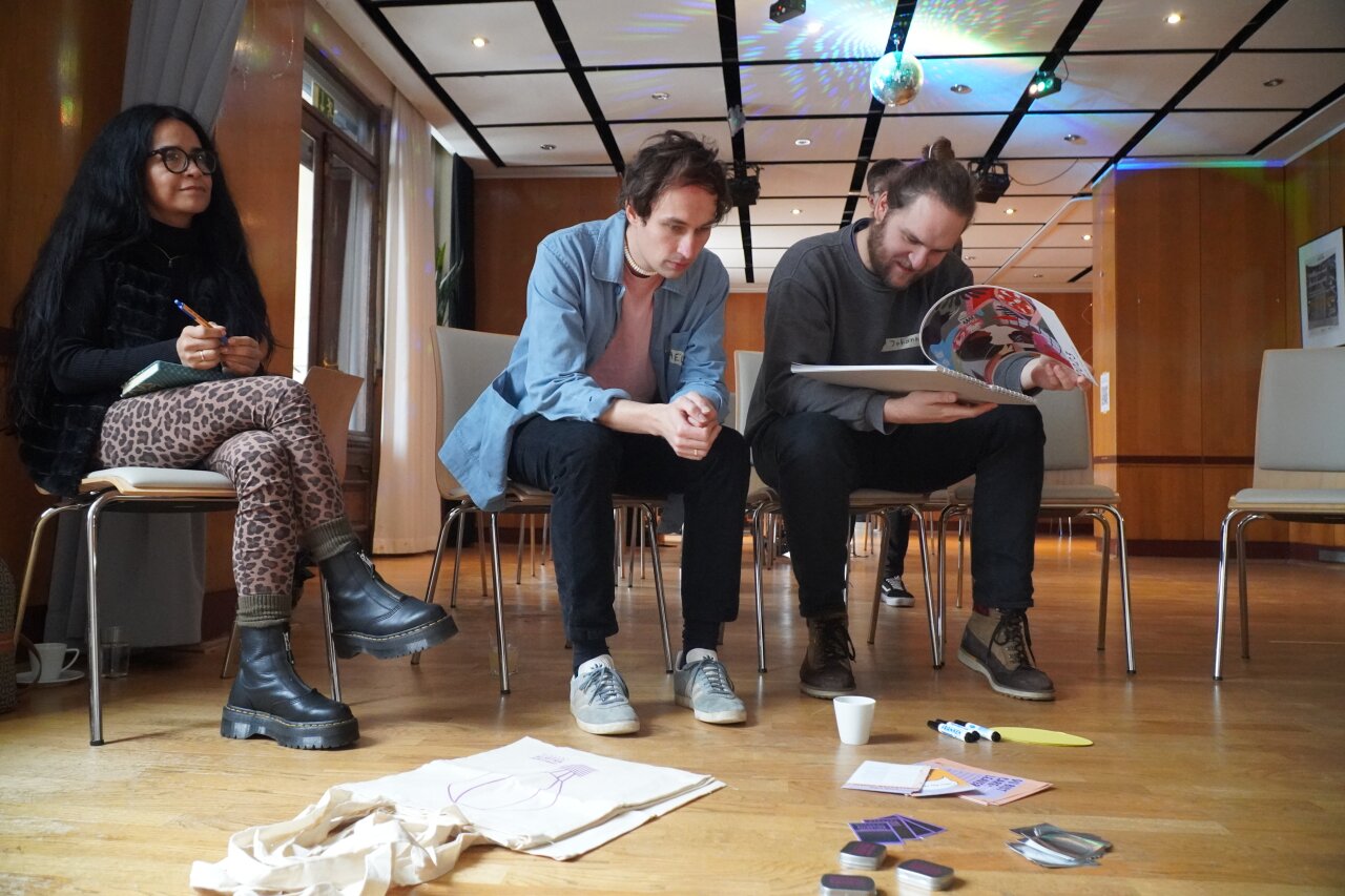 Teilnehmende beim Barcamp schauen sich Infomaterial an.